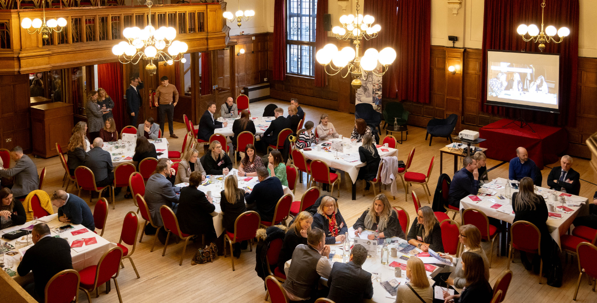 Adults sitting at round tables at a conference