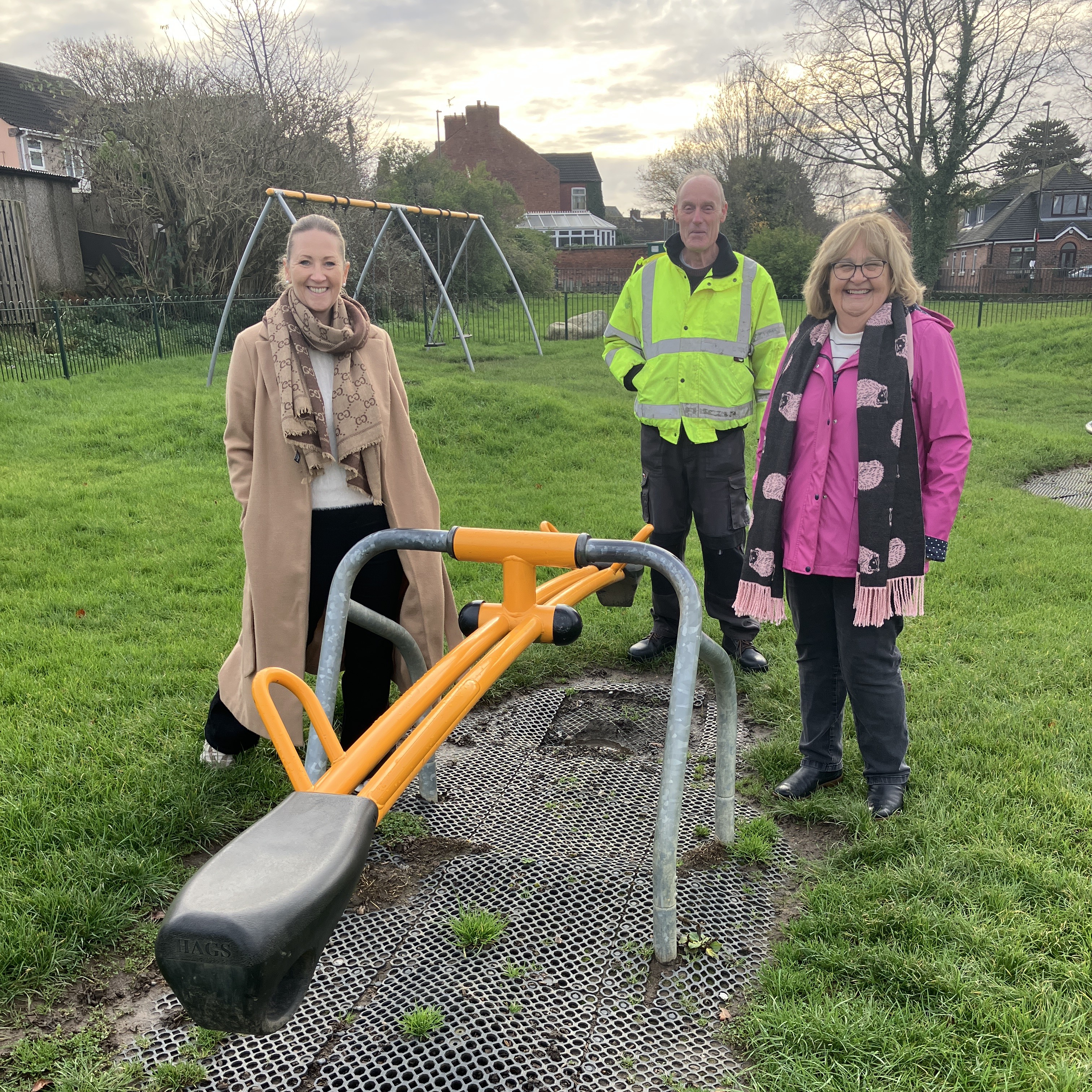 Friends of Thistle Park stood with play equipment and surfacing that has worn