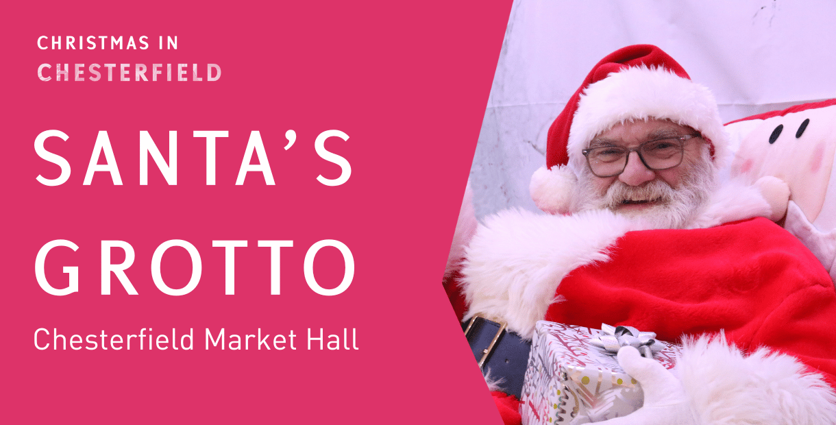 Santa in his red suit sat in an armchair waving