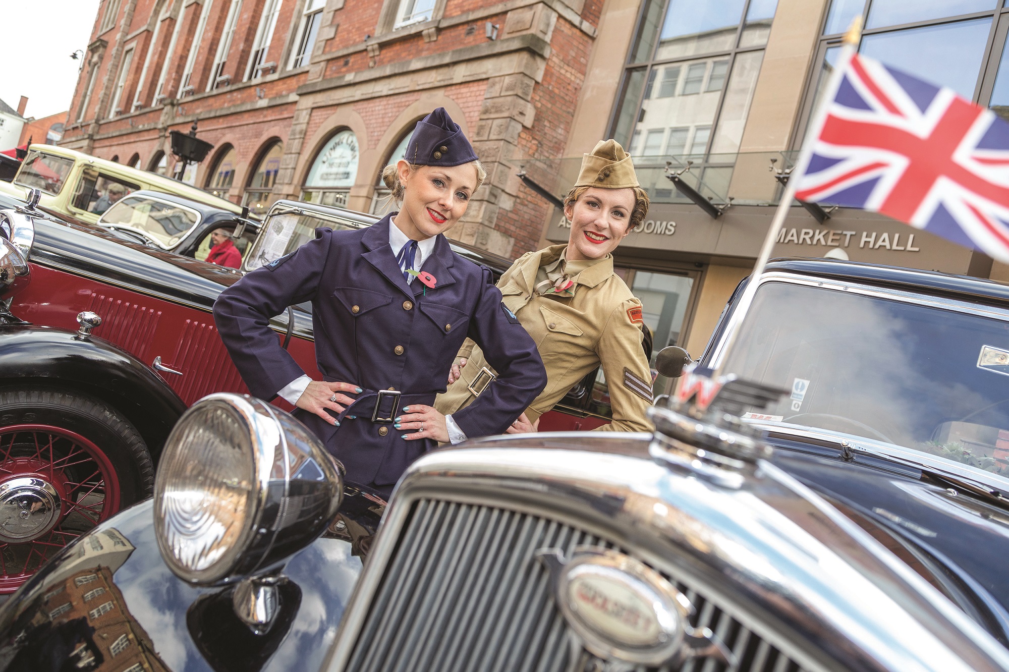 Entertainment at a previous 1940s market - ladies in 1940s clothing stood next to classic cars 